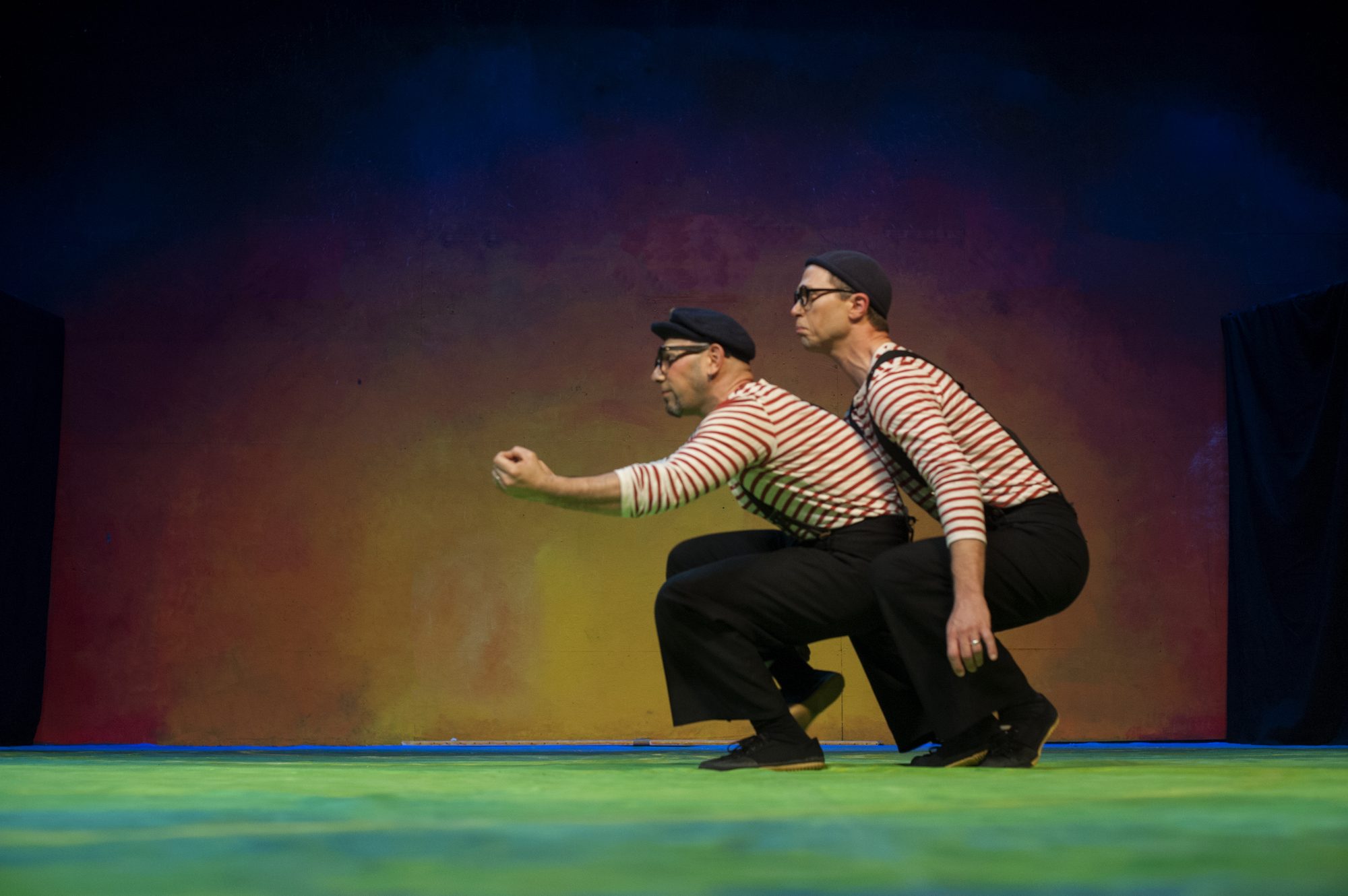 Jaron and Slater in striped sailor shirts, crouched in tandem as a submarine on a painted rainbow stage
